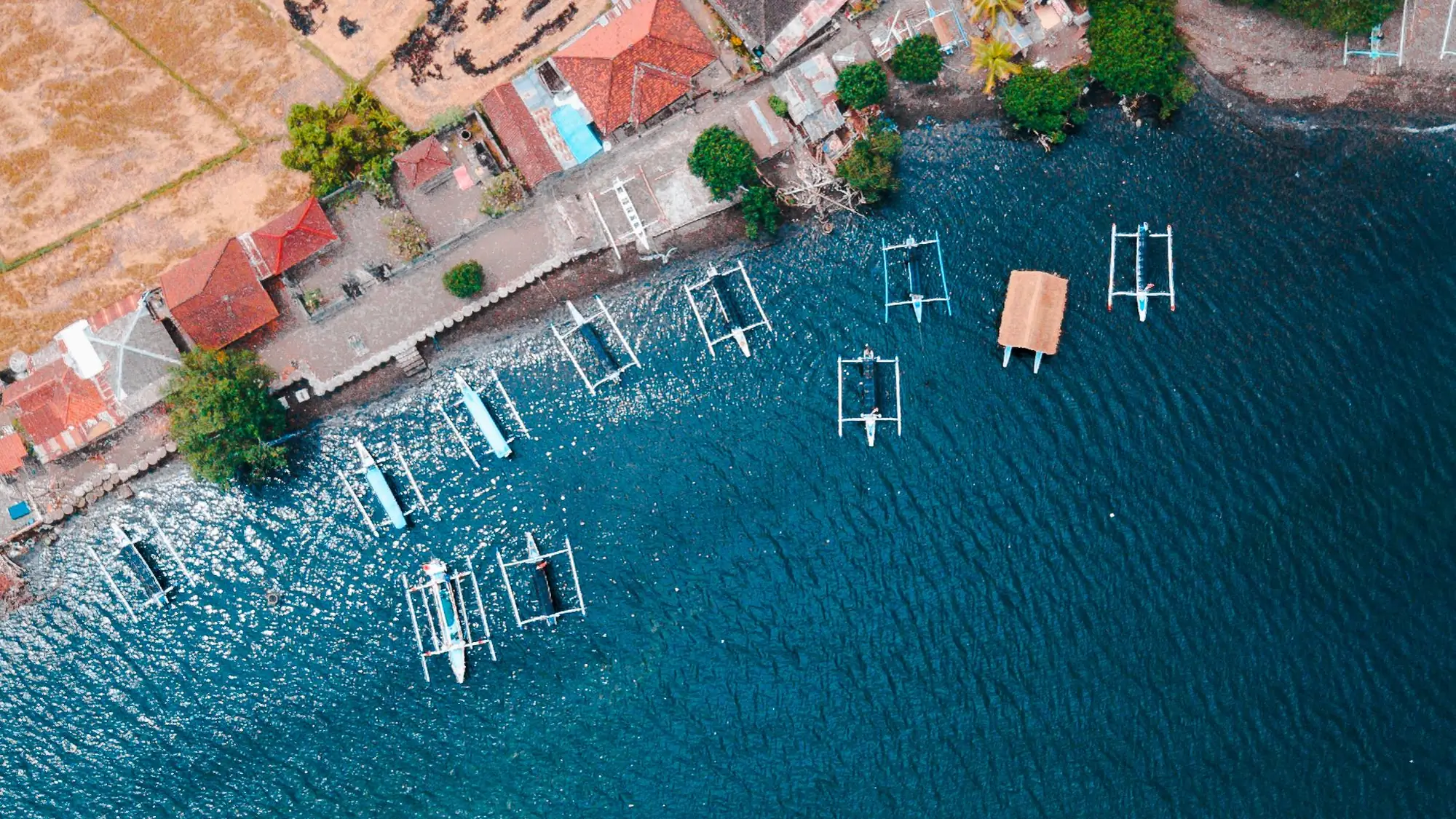 Aerial view of the Buleleng coastline with houses, boats and blue sea
