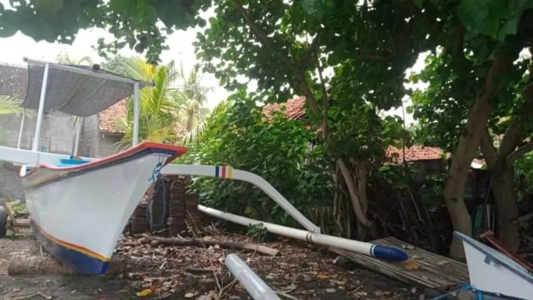 Traditional jukung outrigger boats resting on the shore under trees in Lovina, photographed by Balinese Lovina Property