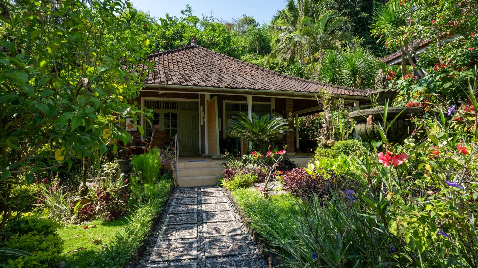 Small Balinese guesthouse with a stone path through a flowering garden